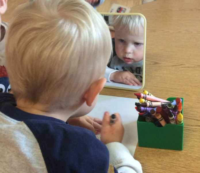 toddler doing a self portrait while looking in the mirror